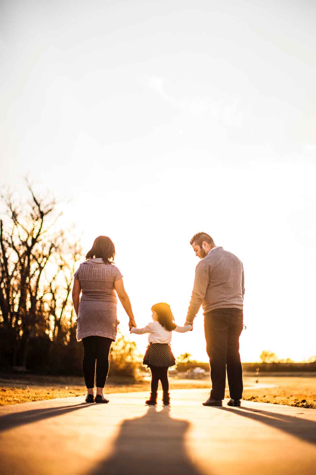 Family holding hands while walking on a path at sunset, representing the importance of home and family in discussions about home insurance savings.