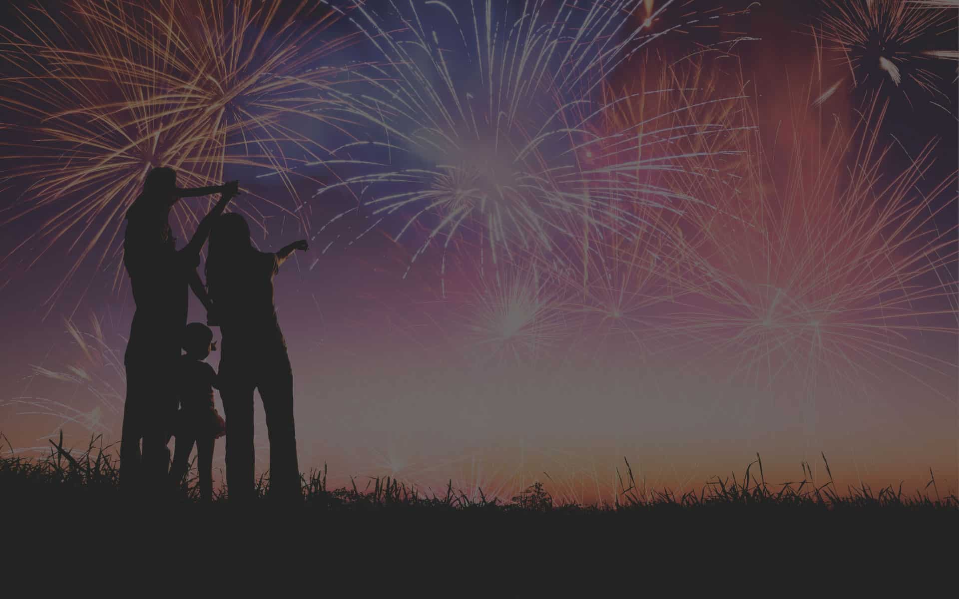 Silhouette of a family watching fireworks against a colorful night sky, symbolizing celebration and togetherness in home buying.